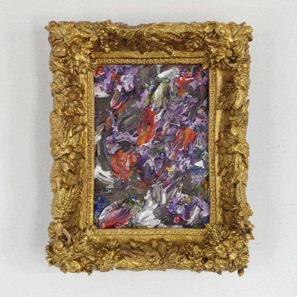 Abstract painting in a gold frame on a white wall