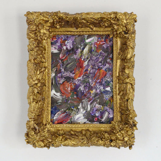 Abstract painting in a gold frame on a white wall