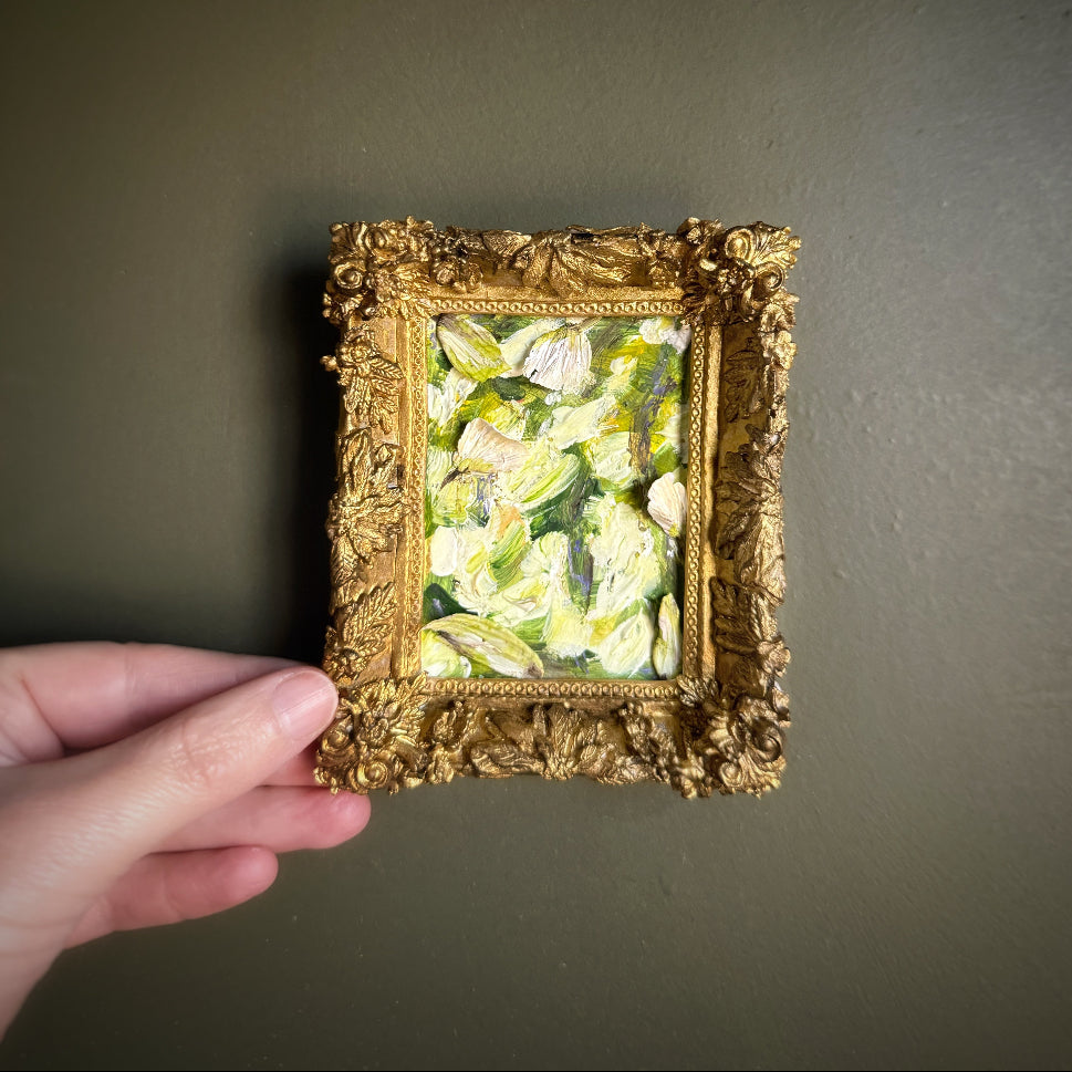 Gold-framed artwork held against a dark wall